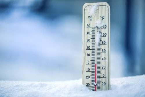 Thermometer on snow shows low temperatures - zero. Low temperatures in degrees Celsius and fahrenheit. Cold winter weather - zero celsius thirty two farenheit.